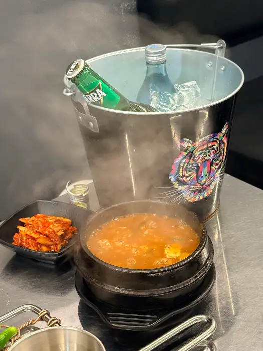 뜨끈한 된장찌개와 곁들임 반찬, 그리고 술병이 놓여있는 모습