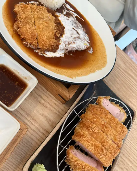 부드러운 속살이 보이는 돈까스 단면과 함께 소스가 곁들여진 모습