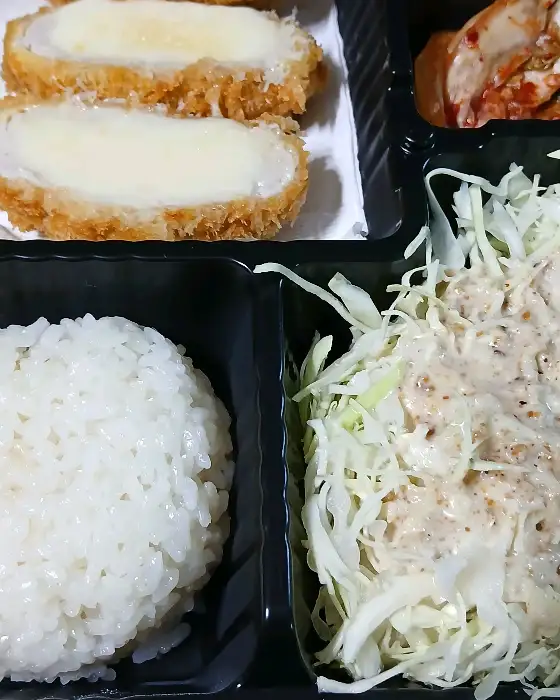 치즈가 가득한 치즈 돈까스와 밥, 샐러드, 김치가 담긴 도시락통