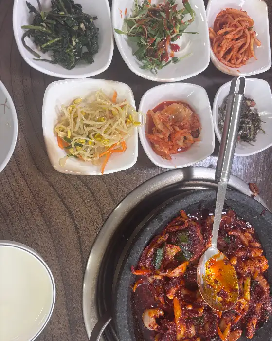푸짐하게 담겨 나온 낙지볶음. 빨간 양념과 함께 각종 반찬들이 보입니다.