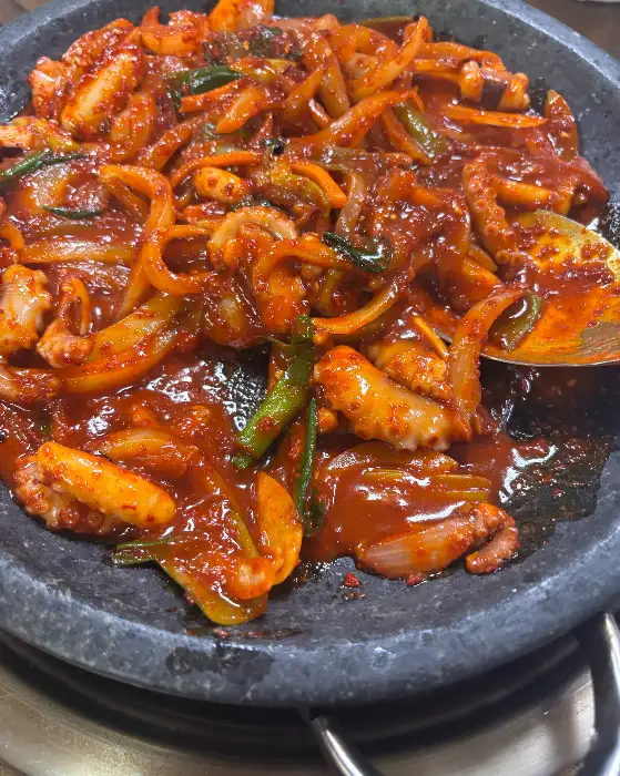 돌판 위에서 지글거리는 낙지볶음. 먹음직스러운 윤기가 흐릅니다.