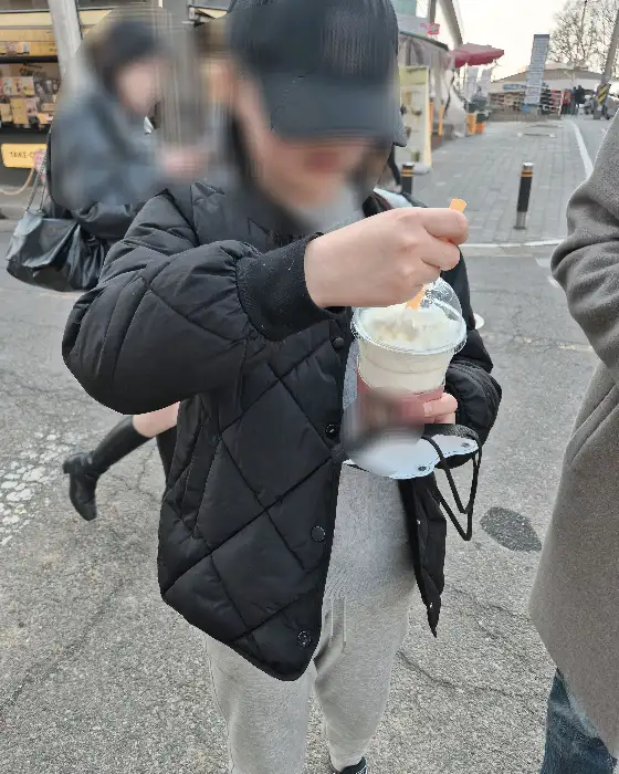 차가운 음료가 담긴 컵을 들고 있는 사람의 모습. 컵에는 메가커피 로고가 보입니다.