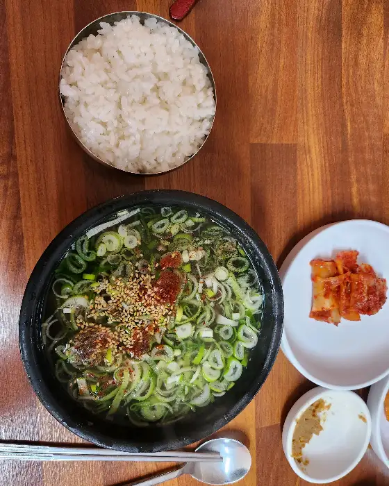 곰탕 한 그릇과 밥, 그리고 김치가 차려진 모습