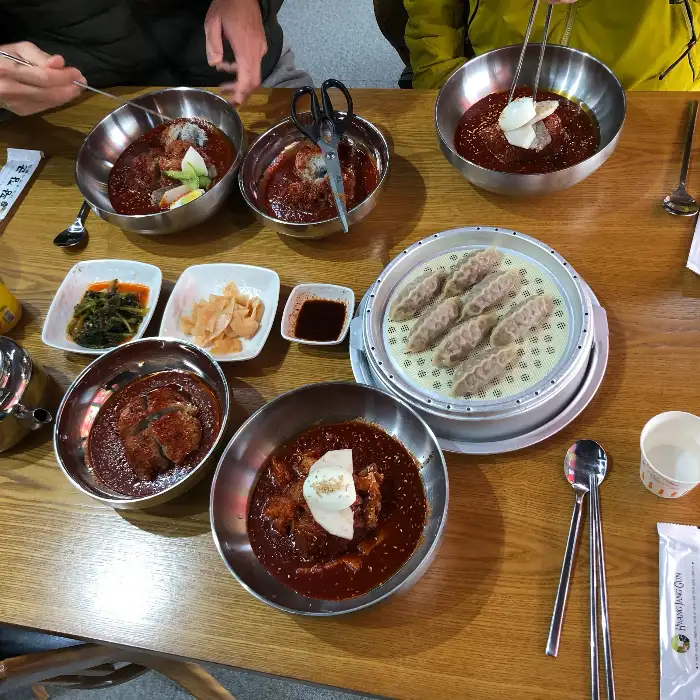 테이블에 놓인 여러 음식들, 만두와 냉면, 그리고 반찬들