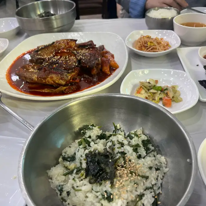테이블 위에 여러 반찬과 함께 곤드레밥이 놓여 있습니다.