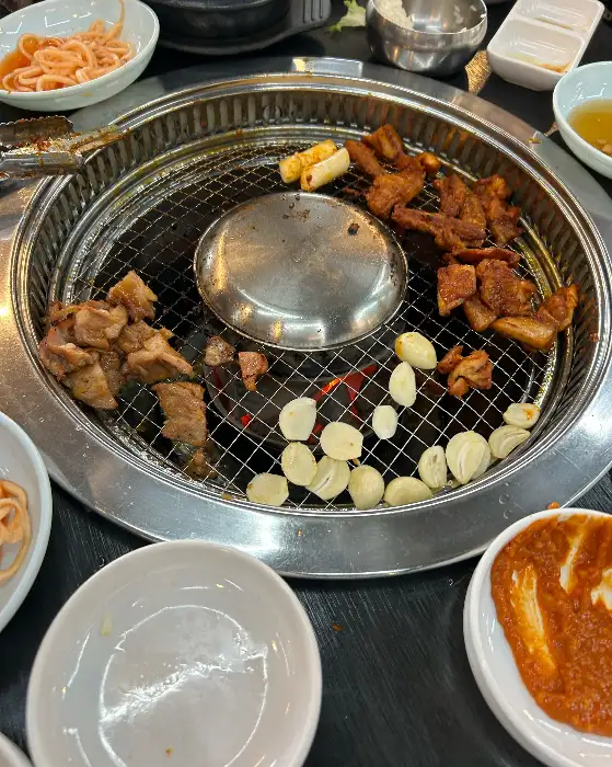 숯불 위에 닭갈비와 치즈, 마늘이 함께 익어가고 있는 모습