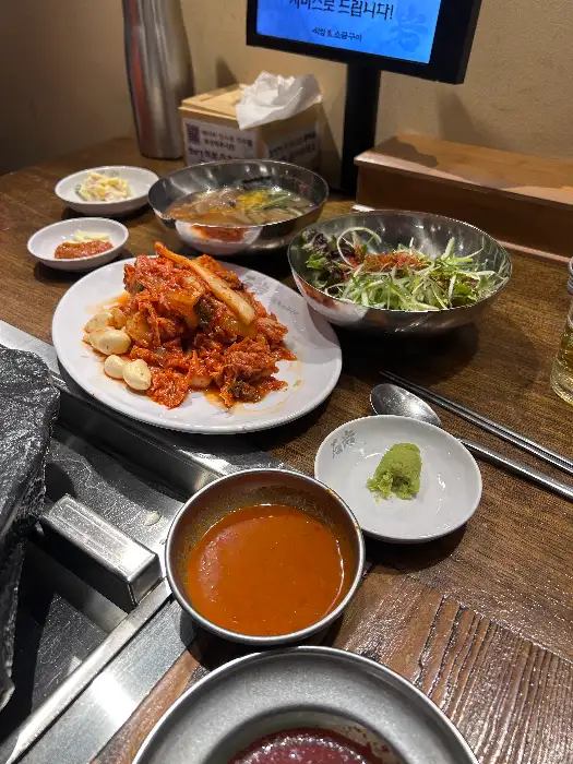 돌판 위에 김치, 마늘, 고기가 함께 구워지고 있는 모습