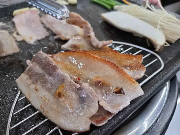 불판 위에서 맛있게 익어가는 냉삼. 겉은 바삭하고 속은 촉촉합니다.