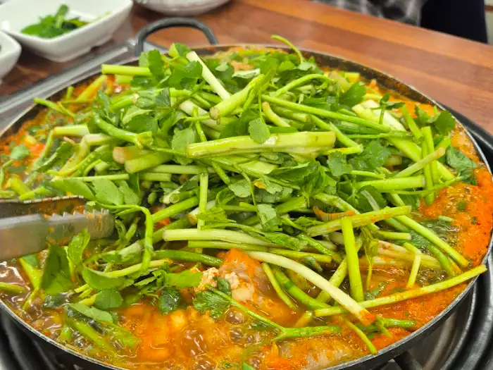 아귀찜으로 보이는 요리가 테이블 위에 놓여있고, 집게로 집으려는 모습