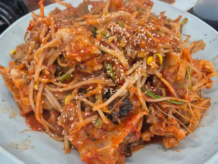아귀찜처럼 보이는 요리가 담긴 접시, 콩나물과 아귀 살이 듬뿍 보임