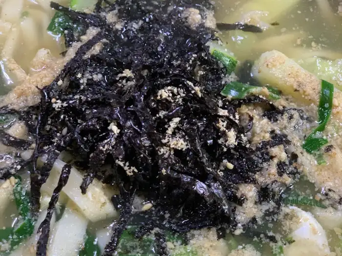 칼국수 그릇에 올라간 김가루와 깨소금, 그리고 국물의 디테일한 모습.