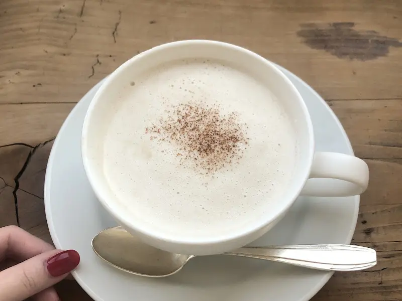 따뜻한 우유 거품 위에 시나몬 가루가 뿌려진 단밤 라떼