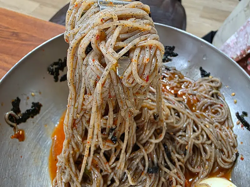 젓가락으로 들어올린 막국수 면발. 윤기가 자르르 흐르는 모습이 식욕을 자극한다.