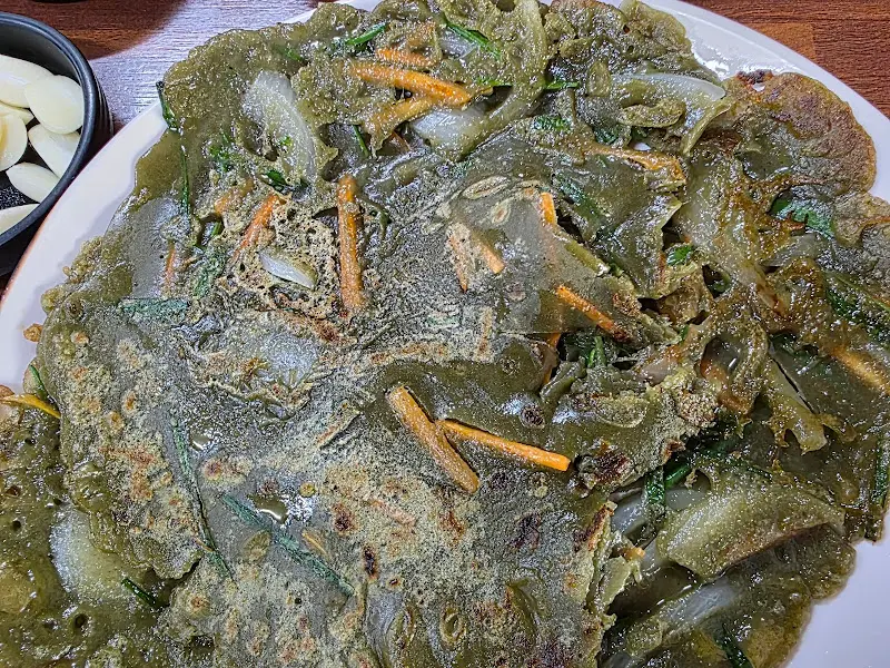 민들레전의 클로즈업 사진. 짙은 녹색 빛깔과 바삭한 겉면이 인상적이다.