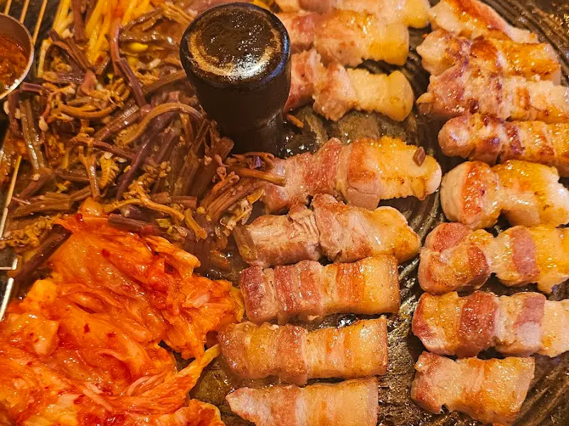 솥뚜껑 위에서 익어가는 목살과 김치, 고사리