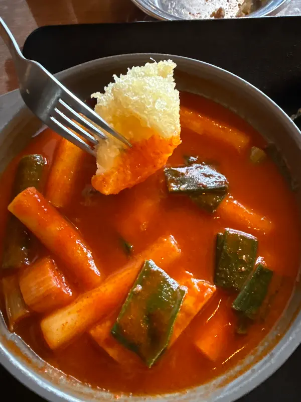 떡볶이 위에 치즈 튀김을 올려 먹는 모습