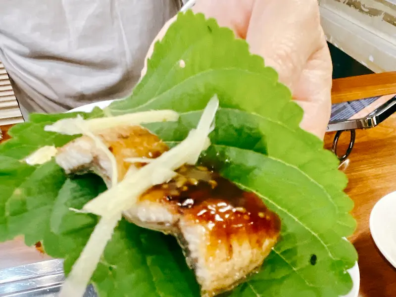 깻잎 위에 쌈을 싸서 손으로 들고 있는 모습