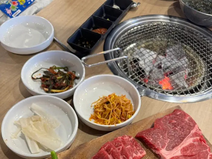 테이블 위에 준비된 숯불 화로, 반찬 그릇들, 그리고 생고기