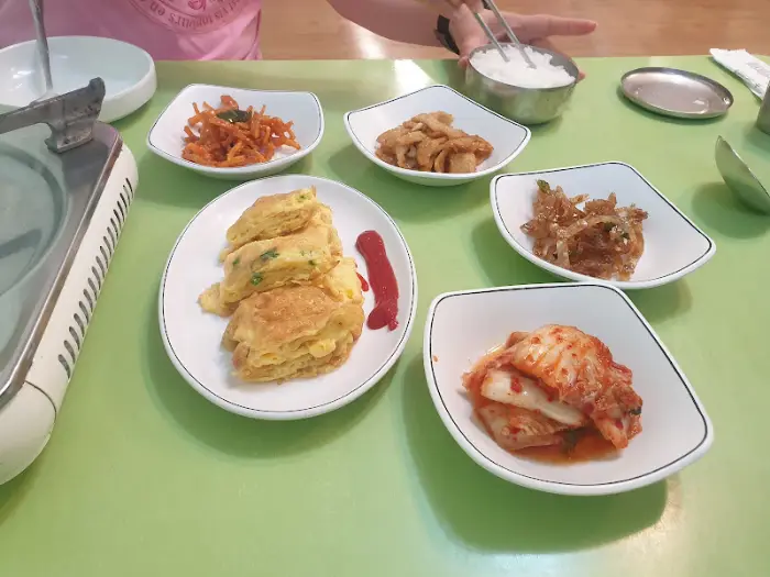 테이블에 차려진 다양한 밑반찬과 밥, 계란말이가 보인다.