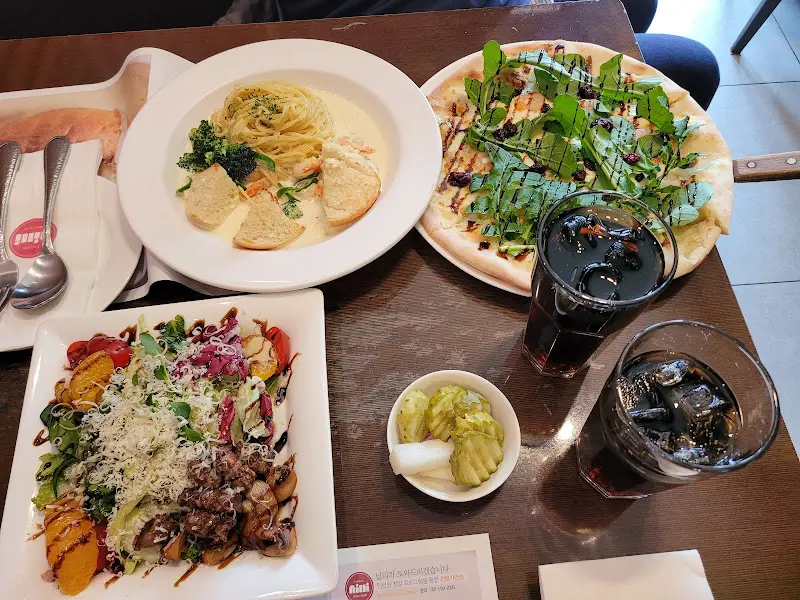 빼쉐, 만죠 샐러드, 음료, 피클, 마늘빵으로 푸짐하게 차려진 테이블