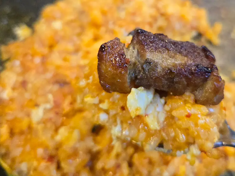 돌판 위에 볶아진 볶음밥 위에 고기가 올려져 있는 모습