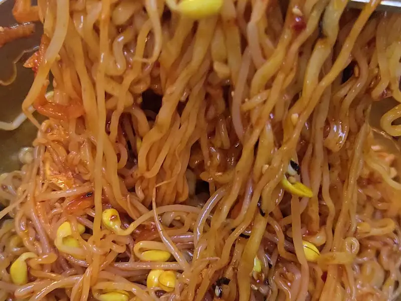 매콤한 비빔면에 올려진 고기 한 점