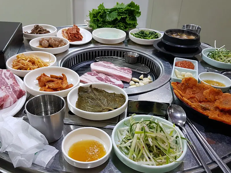 흑돼지 삼겹살과 푸짐한 밑반찬이 가득한 테이블 전경