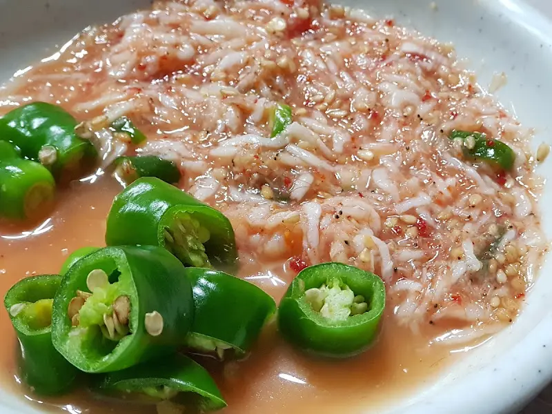 잘게 썰린 새우젓과 청양고추가 담긴 소스 그릇의 클로즈업