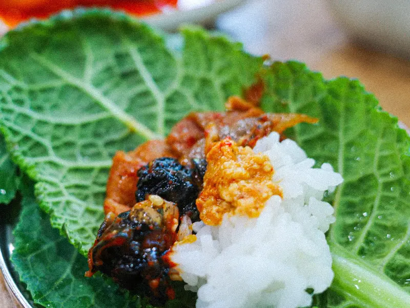 쌈 채소 위에 우렁쌈장, 제육볶음을 올려 크게 한 쌈