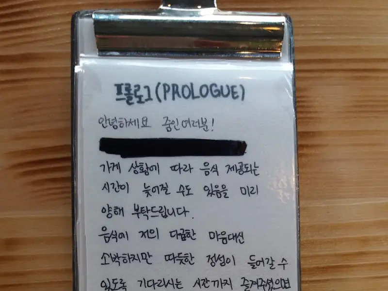 테이블 위에 놓인 메뉴 소개. 손글씨로 정성스럽게 적혀있다.