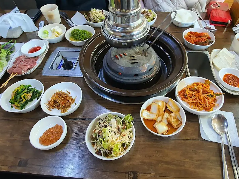 숯불 화로와 다양한 반찬들이 놓여 있는 테이블 전경