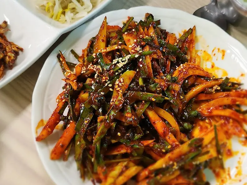 빨갛게 양념된 다슬기무침이 접시에 담겨 있다.