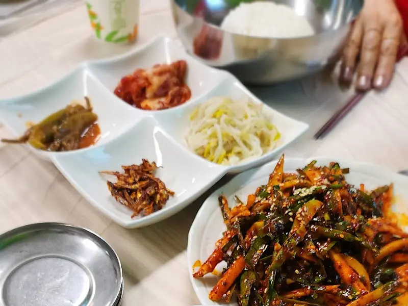 4가지 반찬이 담긴 접시와 다슬기무침, 밥그릇이 테이블 위에 놓여 있다.