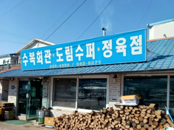 가게 앞 전경, 파란색 간판과 함께 겹겹이 쌓인 장작들이 보인다.
