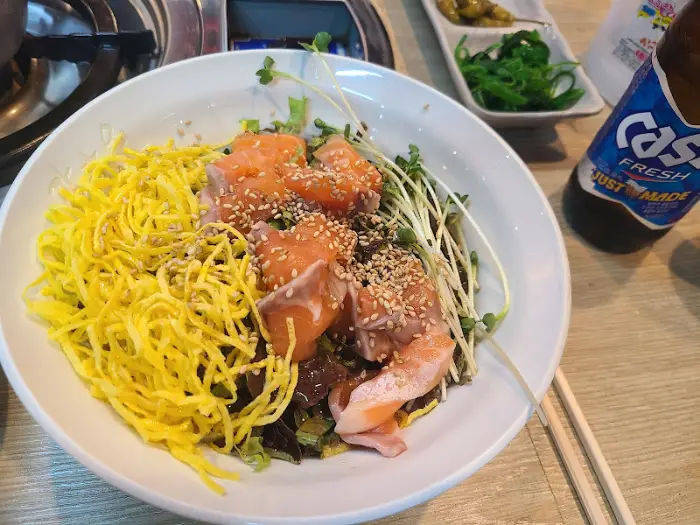 연어덮밥과 곁들임 반찬, 그리고 맥주병이 놓인 모습