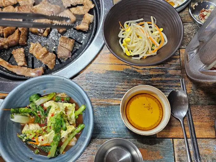 숯불 위에서 익고 있는 돼지갈비와 곁들임 찬들 (다른 각도)