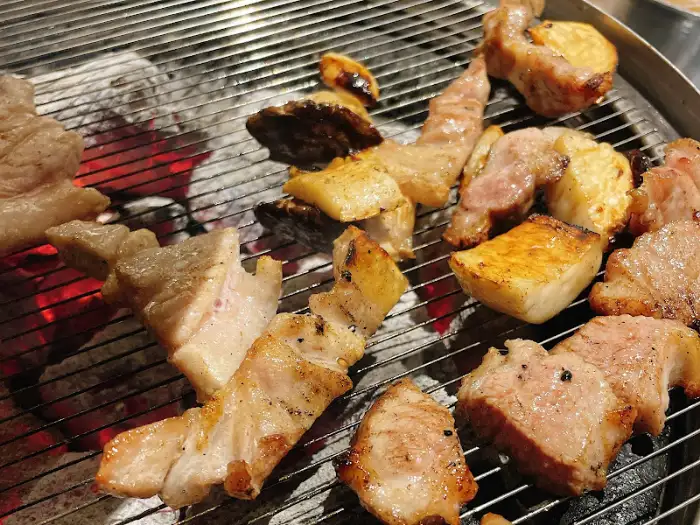 숯불 위에서 맛있게 익어가는 돼지고기 조각들