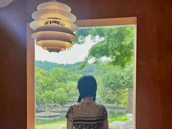 창밖으로 보이는 푸른 나무와 연못. 여유로운 풍경이 펼쳐진다.
