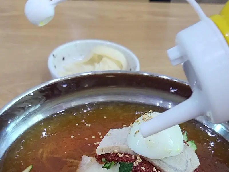 밀면에 겨자를 뿌리는 모습