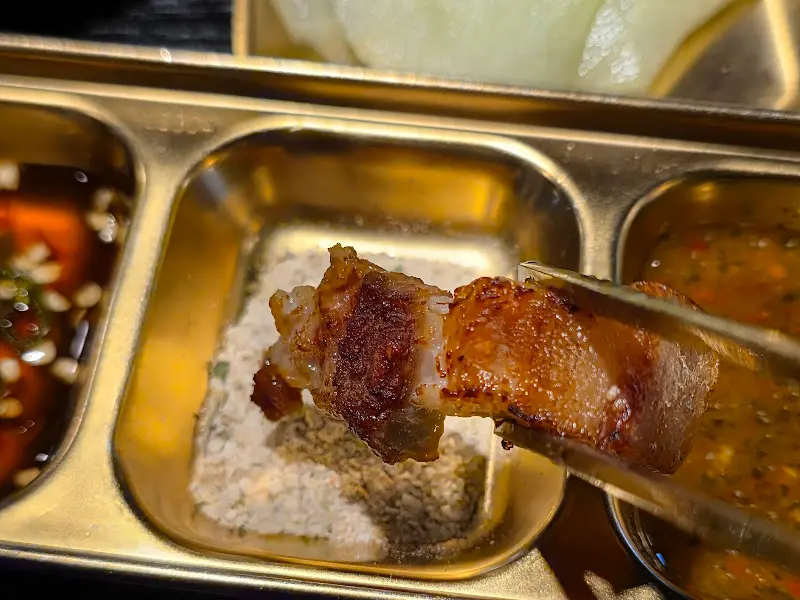 잘 구워진 삼겹살을 소스에 찍어 먹는 모습