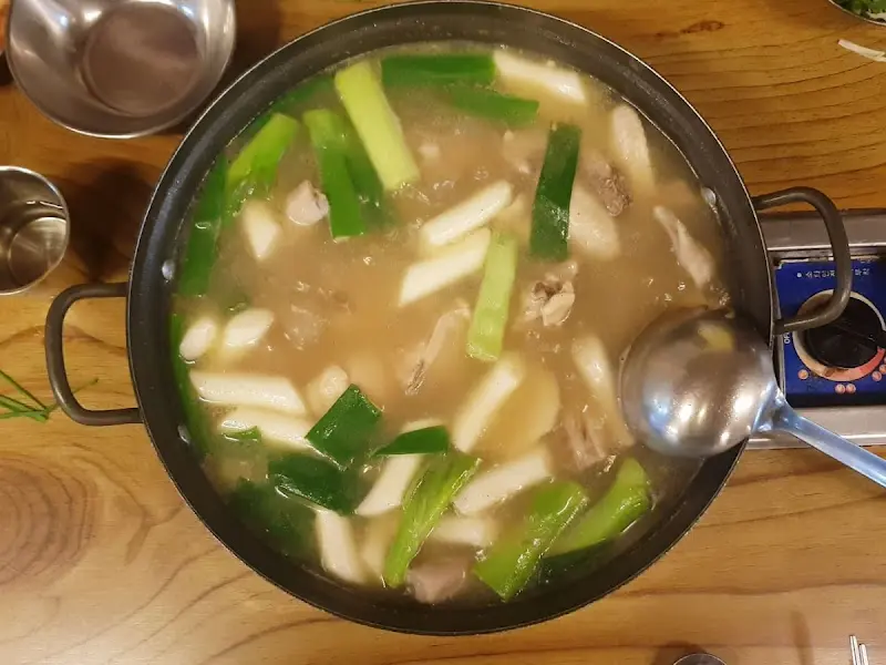 뽀얀 국물 속 닭고기와 떡, 파가 담긴 닭한마리 냄비