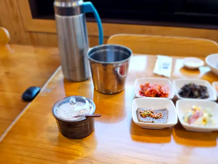 테이블에 차려진 여러 가지 밑반찬과 물병, 컵