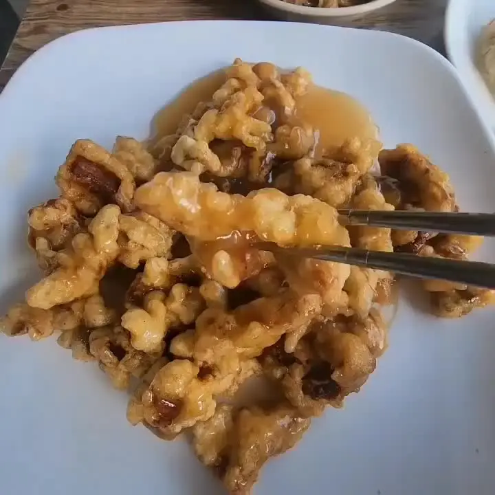 윤기가 흐르는 탕수육을 젓가락으로 집어 올리는 모습