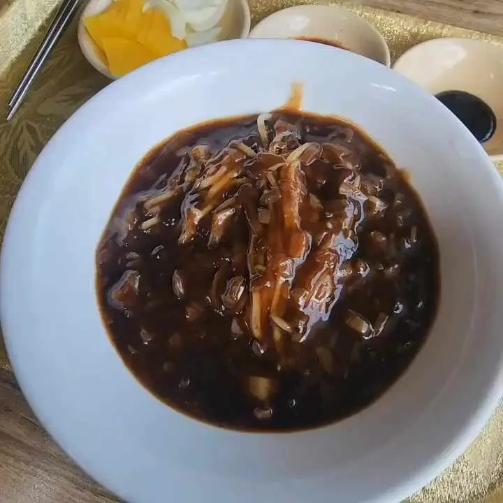 윤기가 흐르는 짜장면 위에 얹어진 채썬 오이 고명