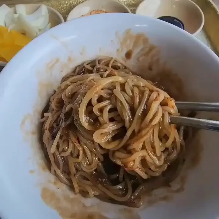 젓가락으로 짜장면 면발을 들어올리는 모습