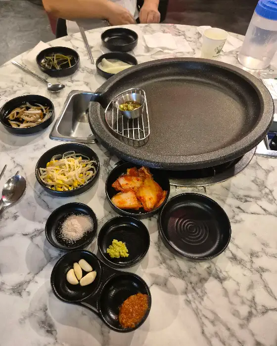 불판 주변에 세팅된 콩나물, 김치, 마늘, 쌈장 등