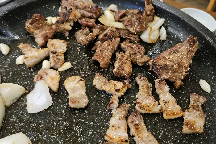 돌판 위에 가지런히 놓인 돼지갈비와 마늘