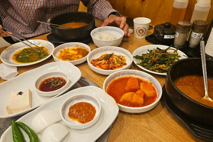 식탁에 차려진 다양한 밑반찬과 흑염소탕