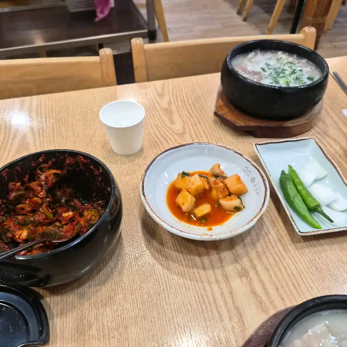 테이블 위에 놓인 순대국, 깍두기, 김치, 고추 등의 반찬