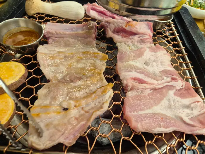 숯불 위에서 익어가는 생갈비와 곁들임용 고구마